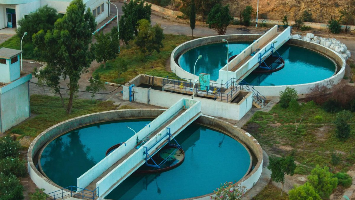 Circular wastewater treatment basins and infrastructure surrounded by greenery